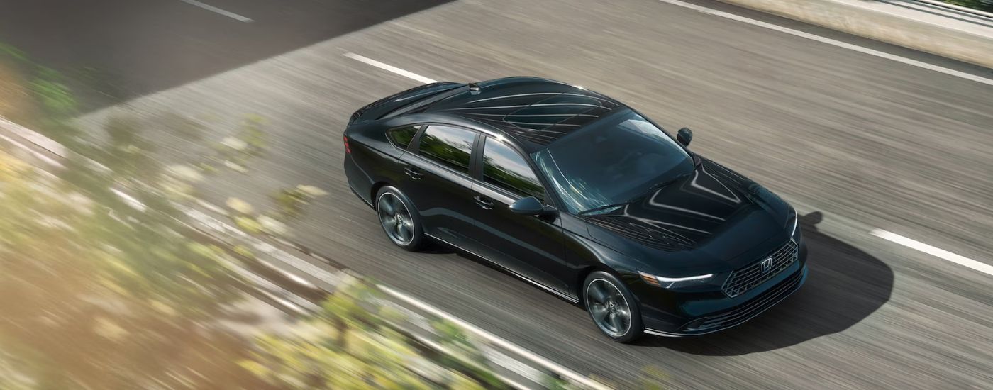 Aerial view of a black 2026 Honda Accord driving on a paved road.