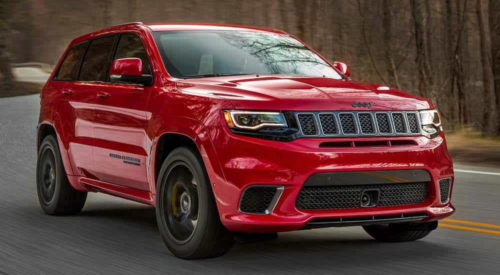 A red 2021 Jeep Grand Cherokee Trackhawk is driving on a winding road to a used car dealer near Shiprock.