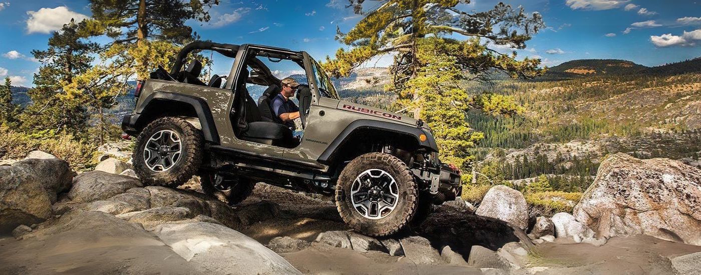 A tan 2017 Jeep Wrangler Rubicon is shown from the side off-road.