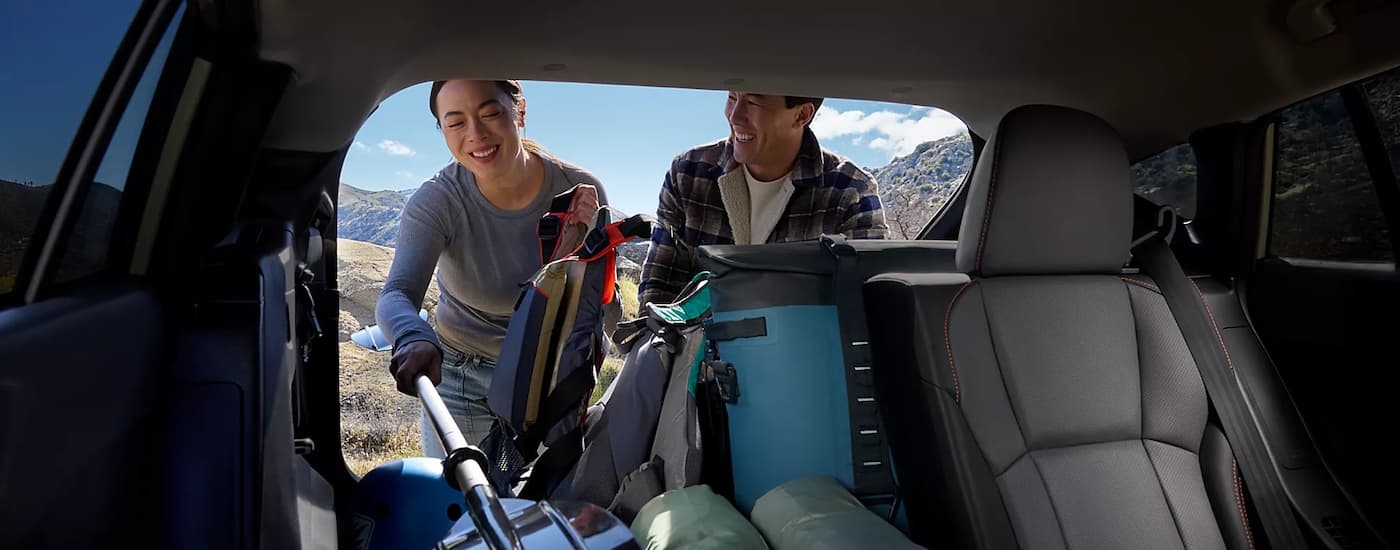 Two people putting kayaking gear into the back of a 2026 Subaru Crosstrek Hybrid.