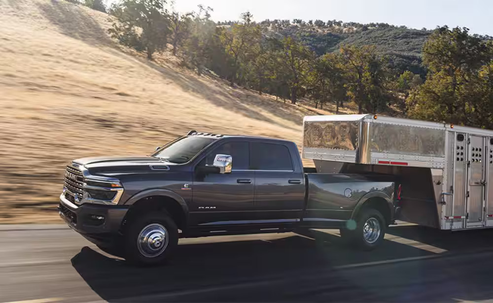 A black truck pulling a trailer on the road.