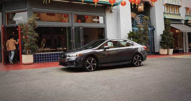 Gray 2023 Subaru Impreza sedan parked outside a storefront