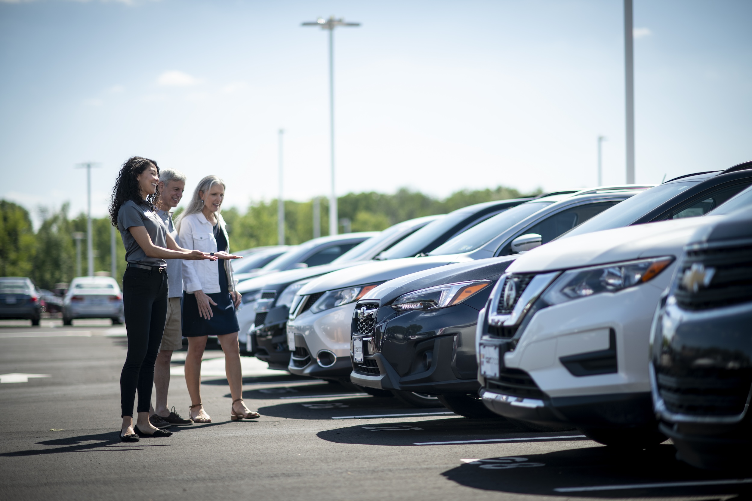 Associate and two customers admiring vehicles in Carshop lot