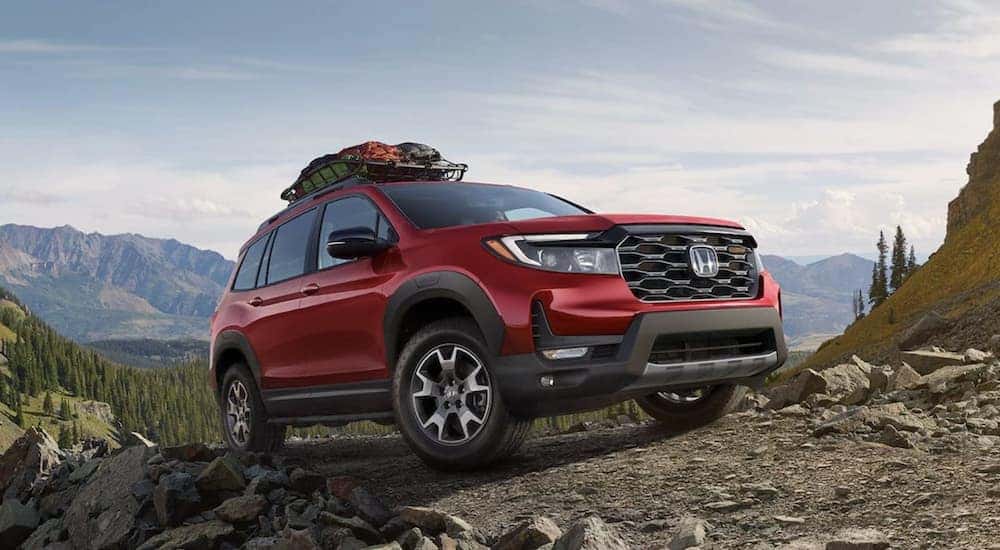 A red 2023 Honda Passport TrailSport is shown parked in the mountains.