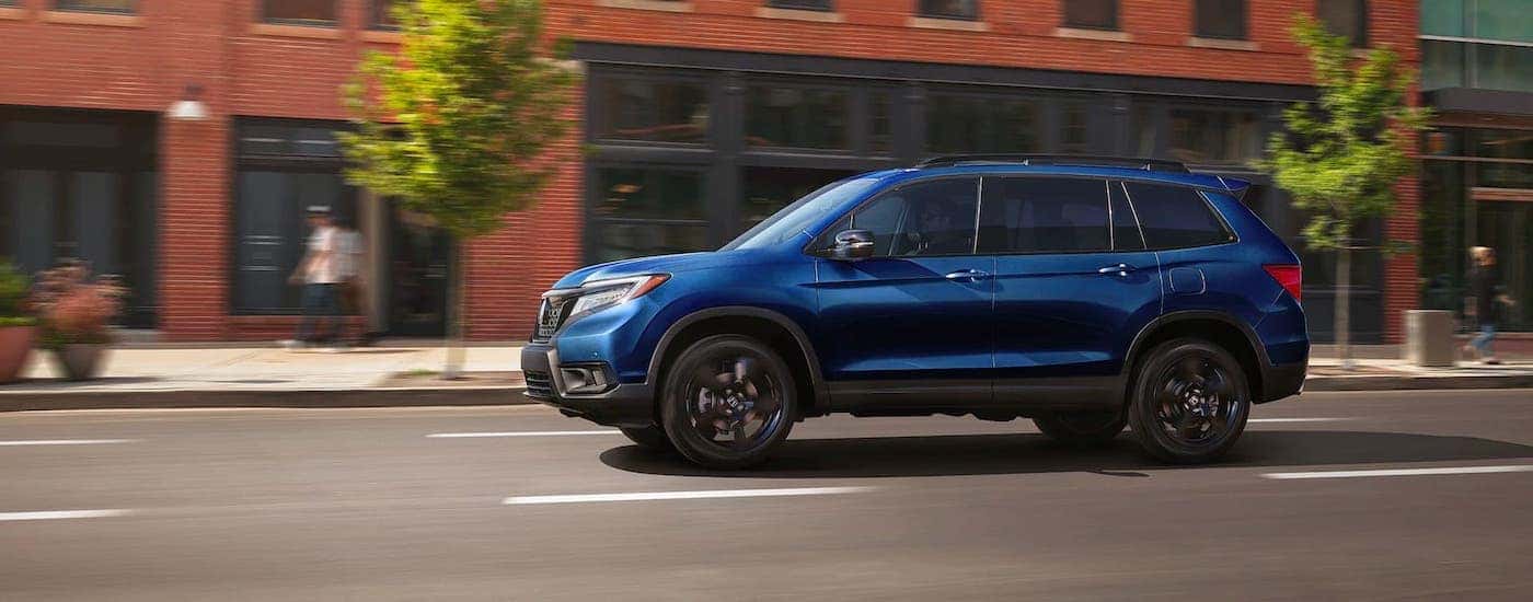 A blue 2020 Honda Passport driving on a city street.