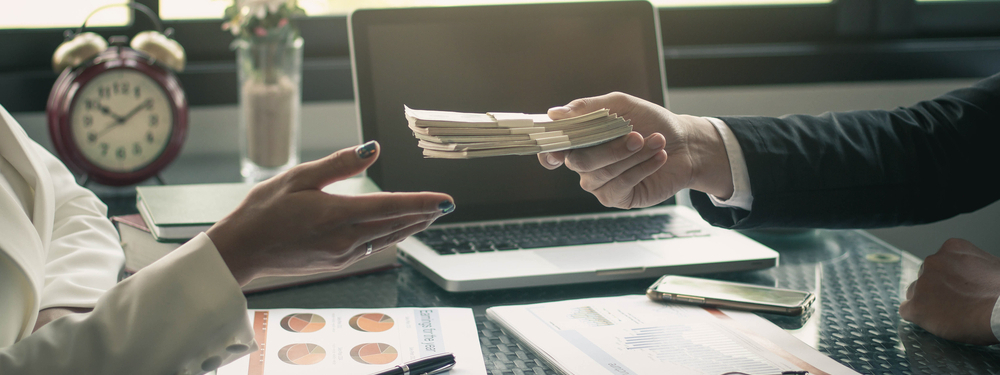 Customer handling cash across a desk to pay for a car