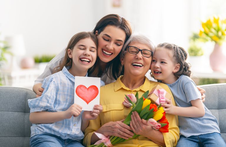 Mom, Grandma and Two Children on a Couch with Mother's Day Card and Flowers