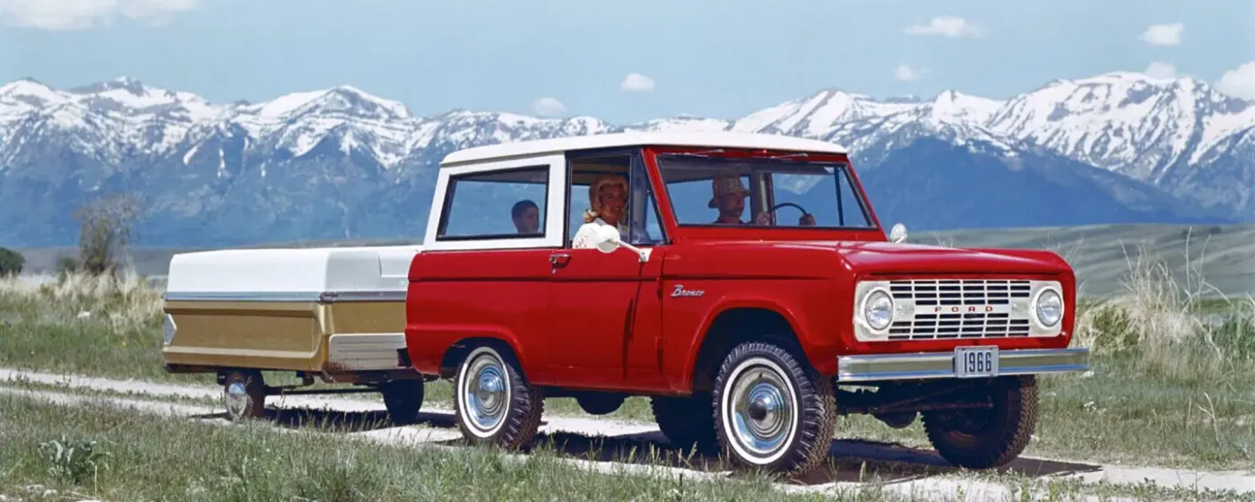 Classic 1966 Ford Bronco towing a pop-up camper on a family road trip