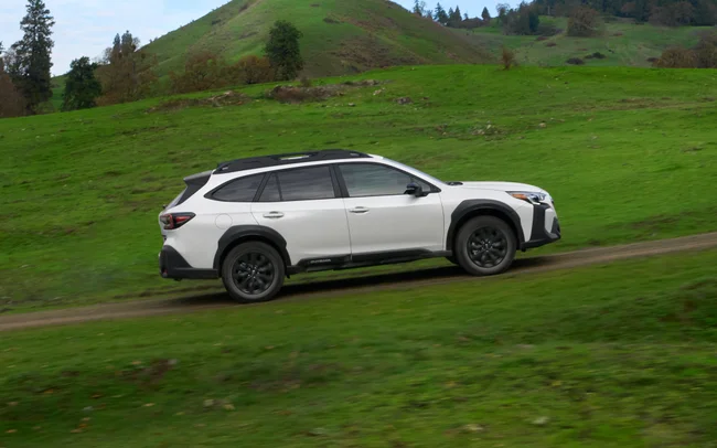 White 2023 Subaru Outback on a grassy hillside