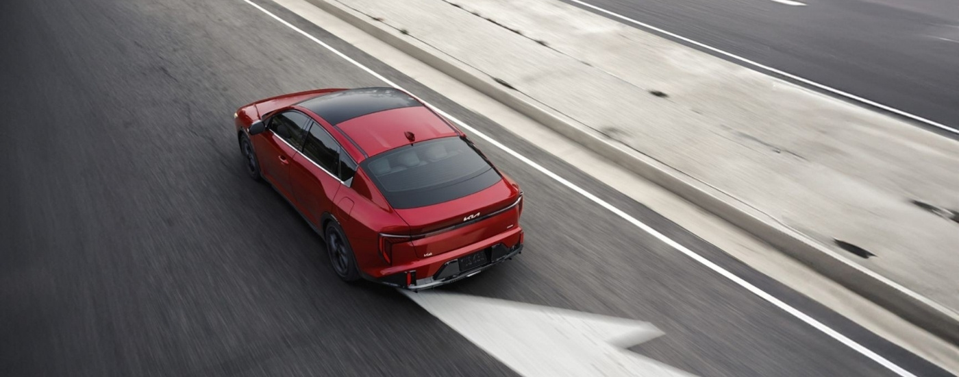 Red 2025 Kia K4 driving on a highway