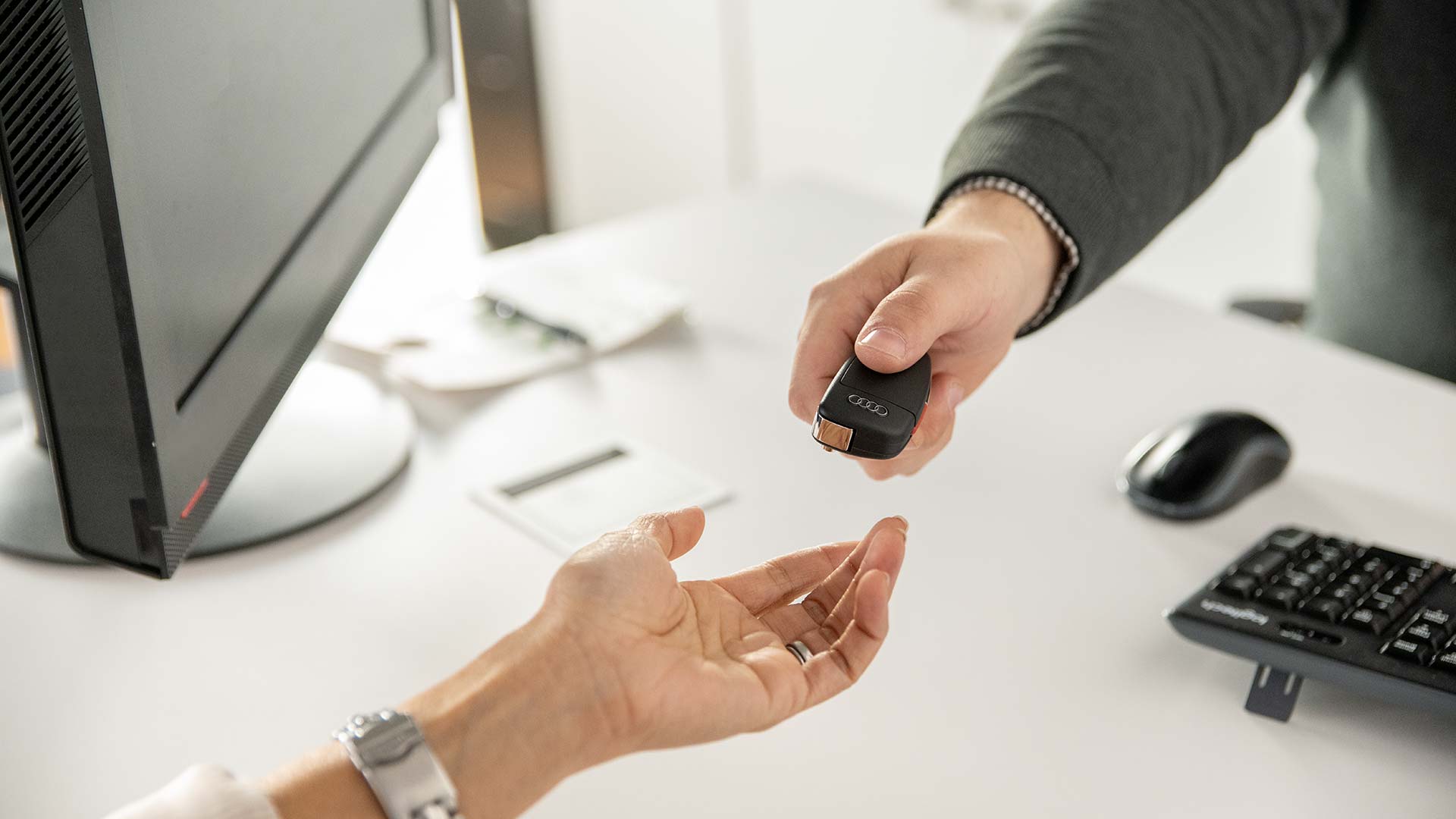 Audi employee handing a set of car keys to a customer.