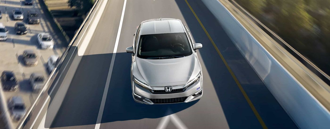 A silver 2020 Honda Clarity Plug-In Hybrid is sown from above driving on a highway overpass near Rochester.