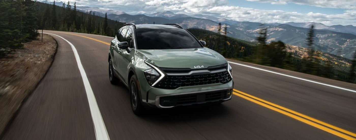 A green 2023 Kia Sportage driving.