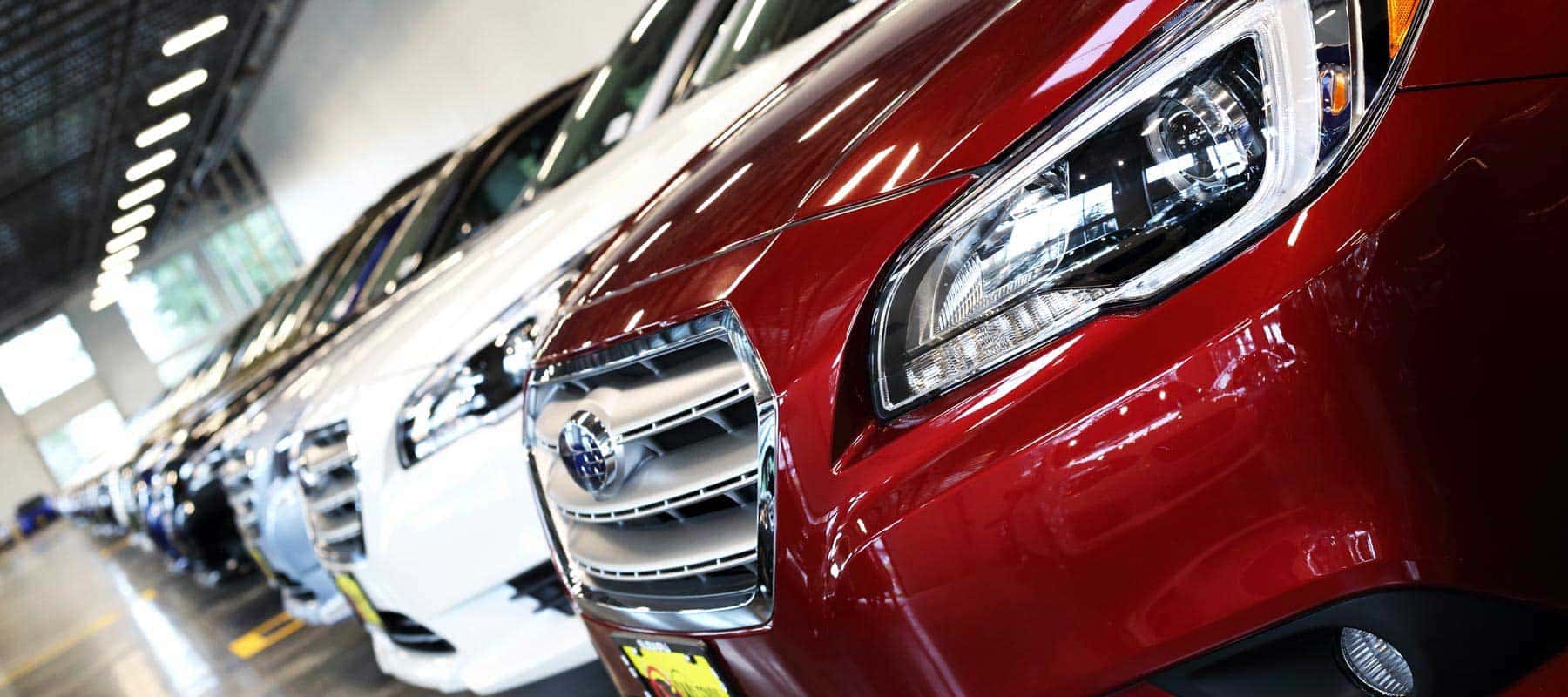 Row of Subaru vehicles with a red Legacy in front