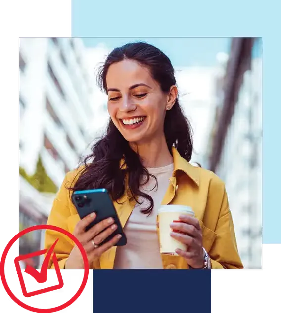 Quick and convenient image. Woman smiling while looking at phone and holding coffee cup in city.