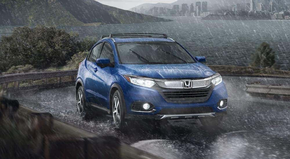 A blue 2024 Honda HR-V EX-L driving down a rainy road.