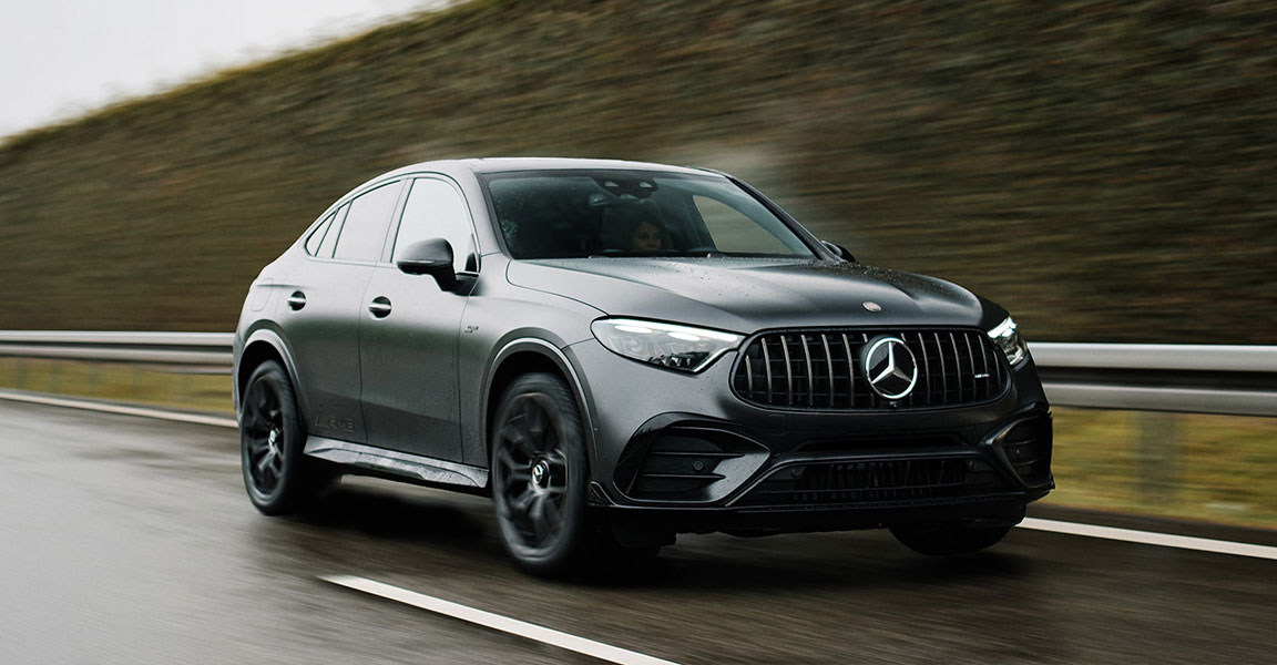 2027 Mercedes-AMG GLC 53 Coupe in black driving on a wet road, front three-quarter view