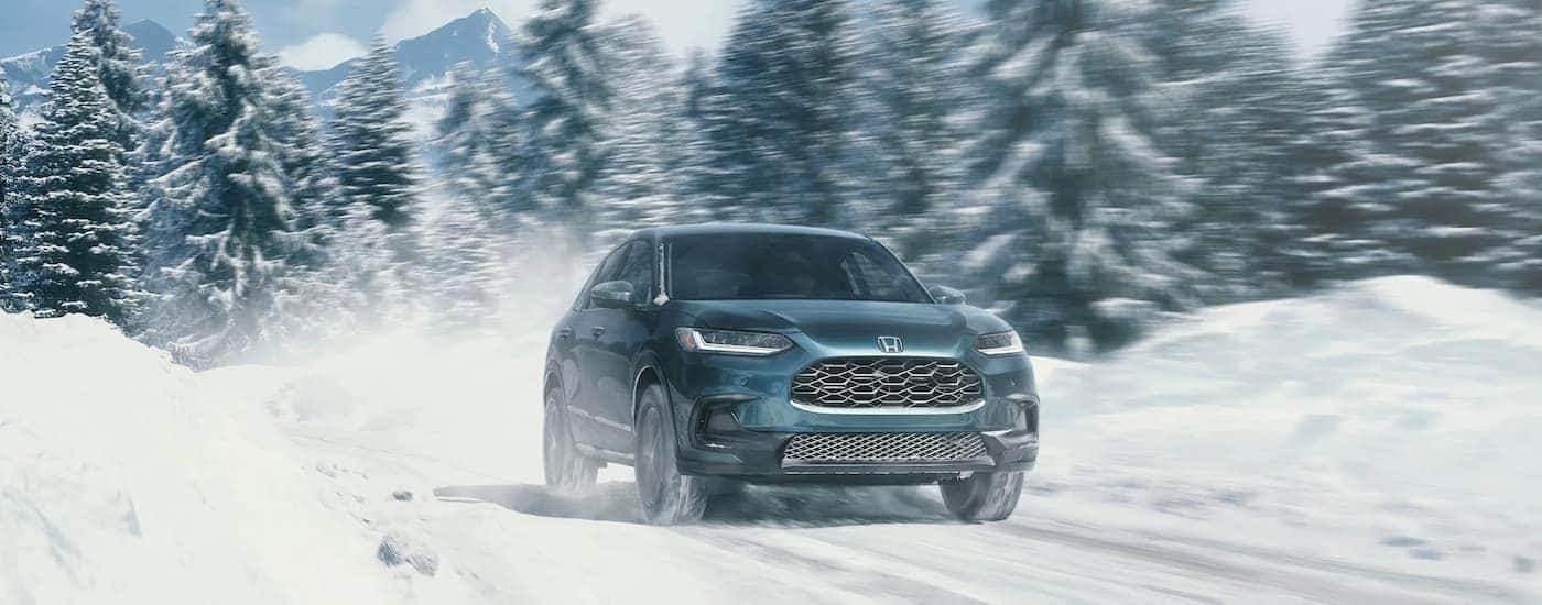 A blue 2023 Honda HR-V EX-L is shown driving on a snowy path.