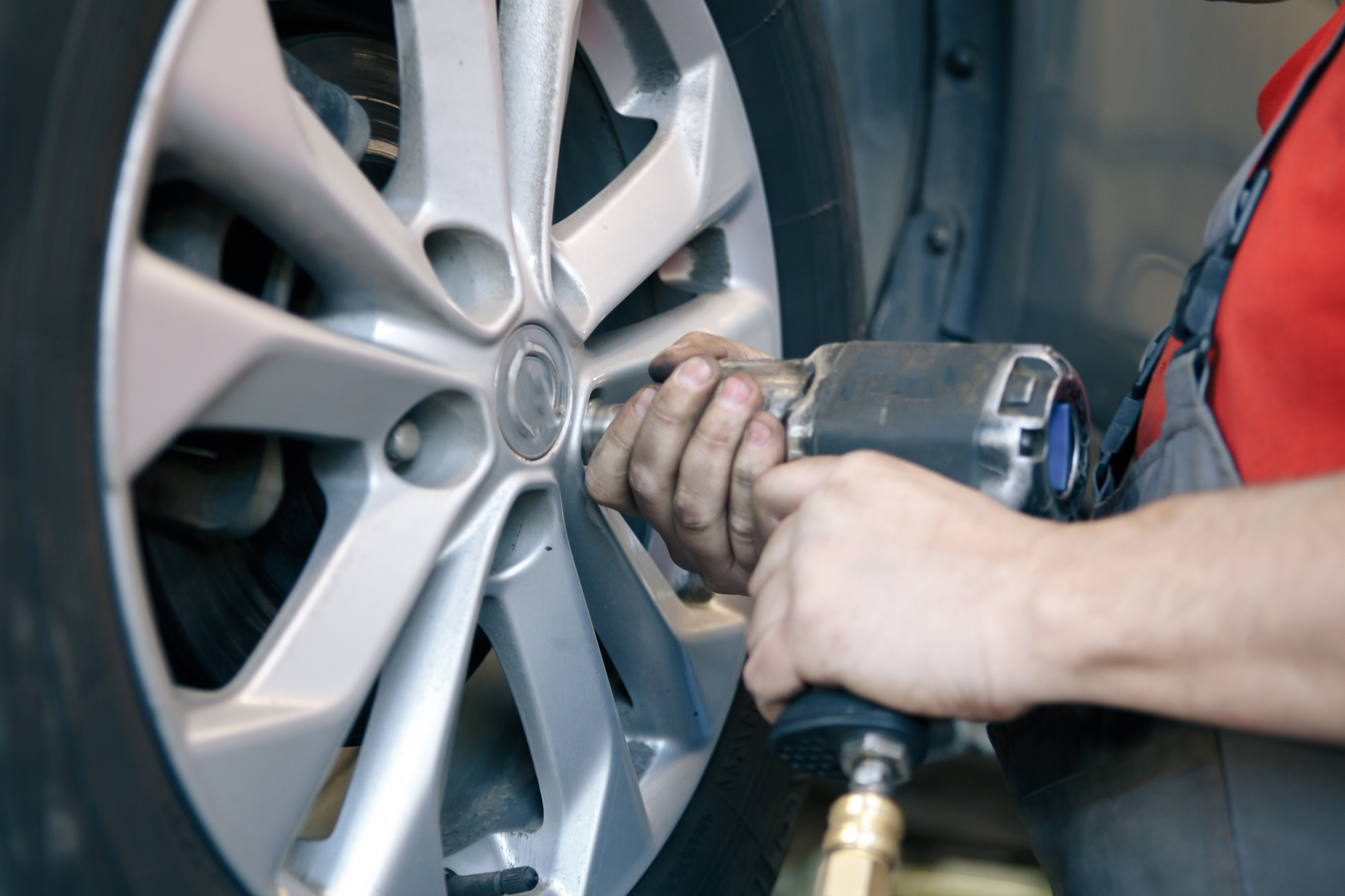 close-up of mechanic's hands, as they tighten the nuts on a vehicle tire