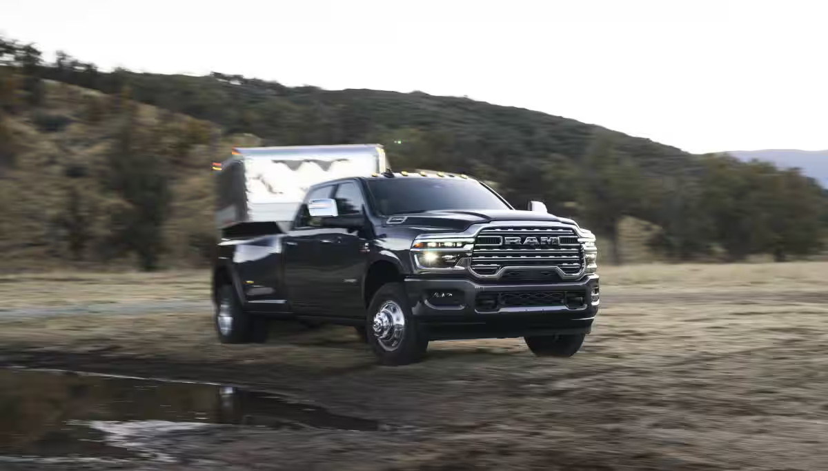 A gray truck pulling a trailer off-road.