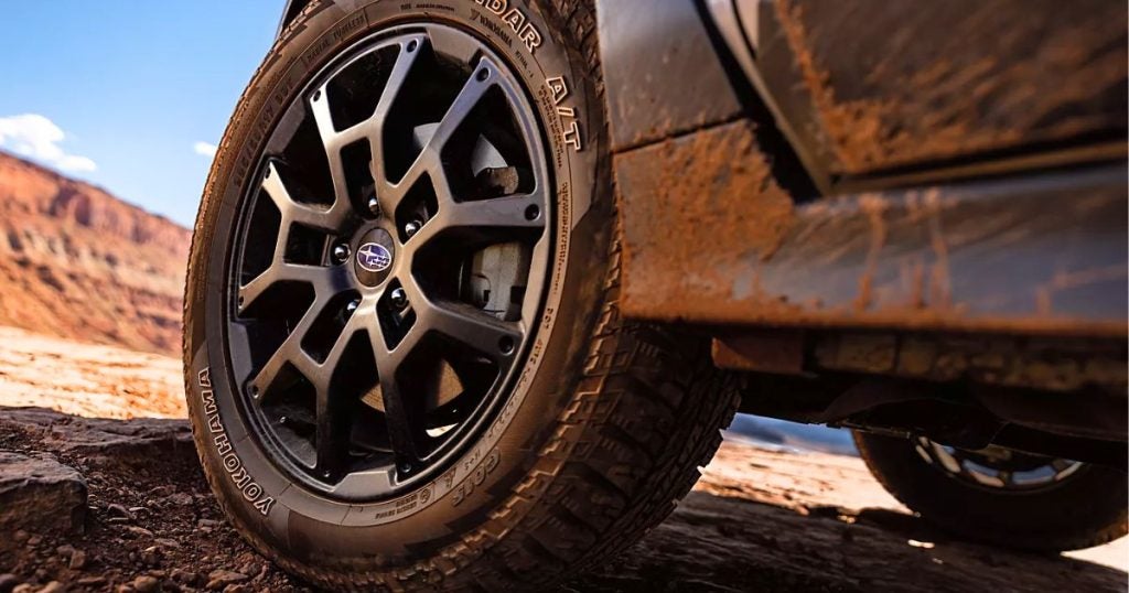 Close-up of a mud-covered Subaru Crosstrek wheel with an all-terrain tire on a desert trail