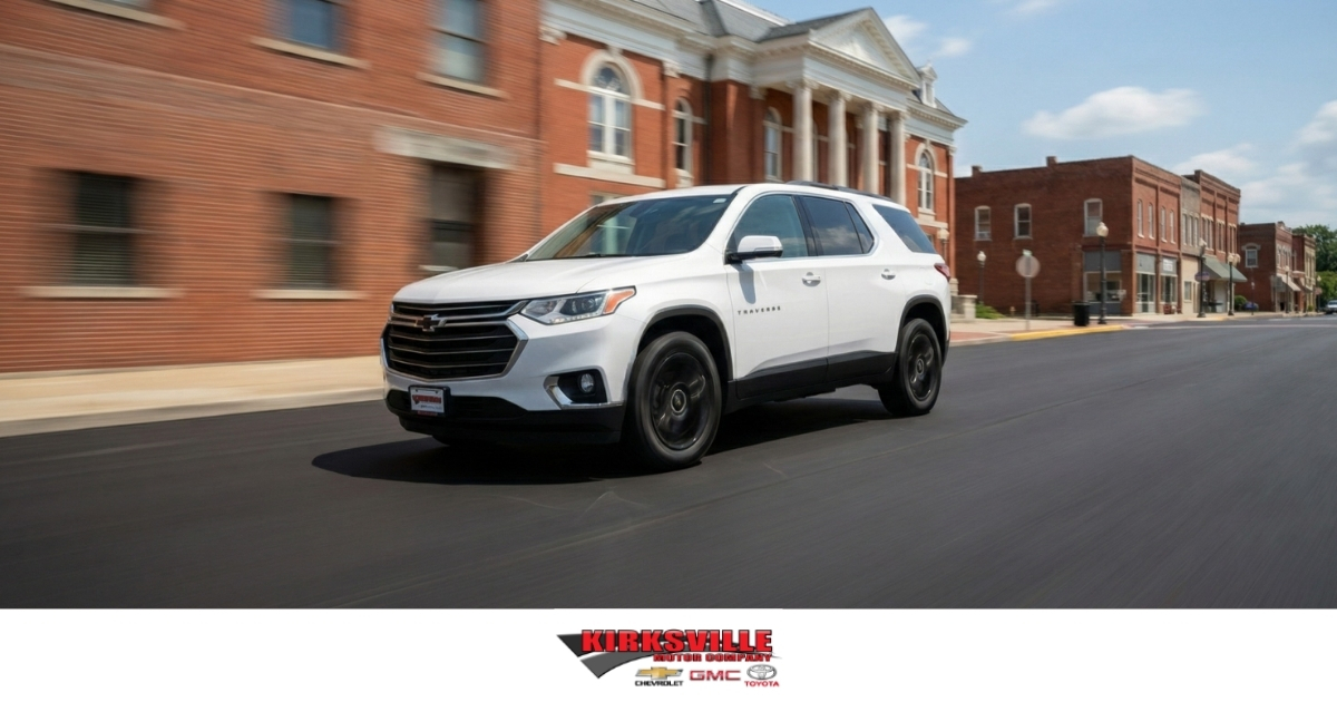 A white Chevrolet Traverse driving through downtown Kirksville, Missouri, representing quality used cars under $20,000 at Kirksville Motor Company.