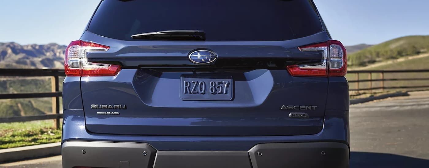 The rear of a blue 2023 Subaru Ascent Onyx Edition is shown with a mountain view.