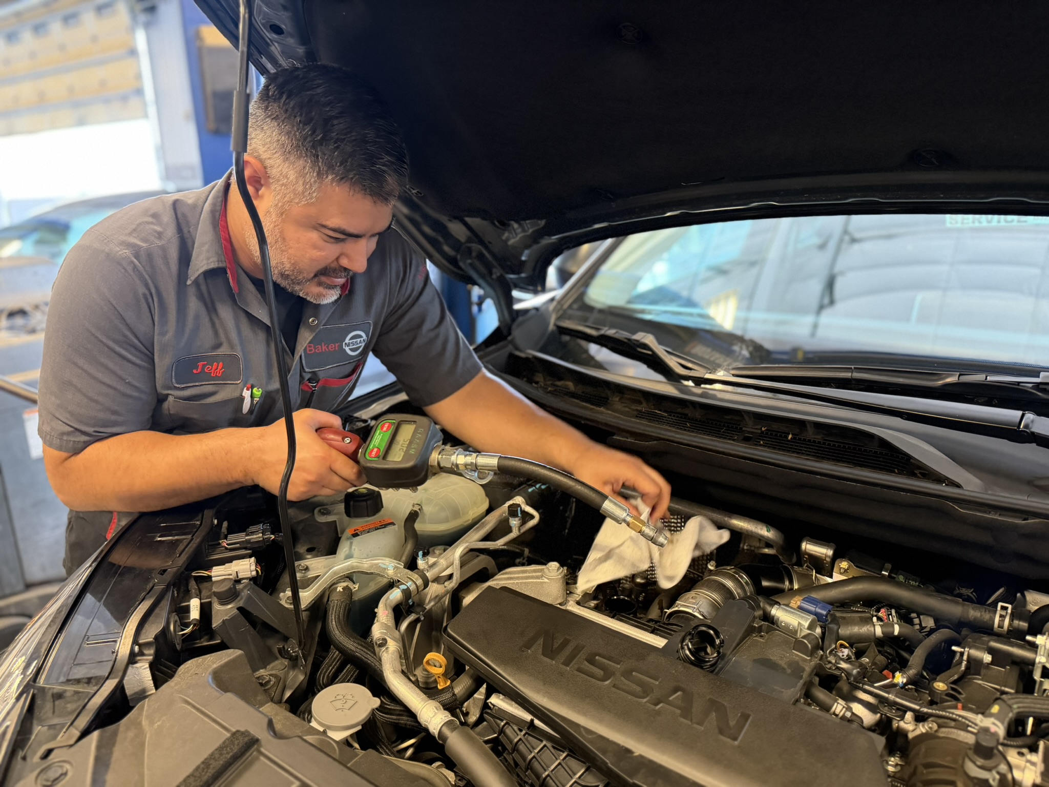Mechanic replacing a Nissan car battery in a dealership service bay