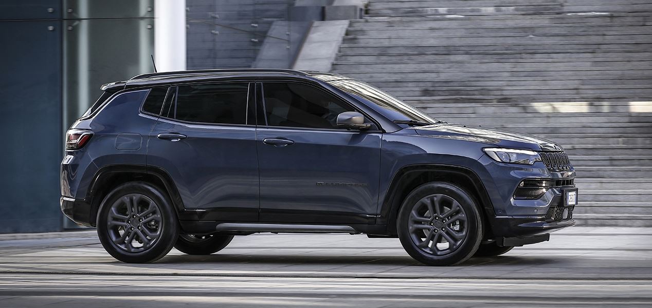 2024 Jeep Compass in dark gray parked on a modern urban street, showcasing its sleek design and bold exterior features.