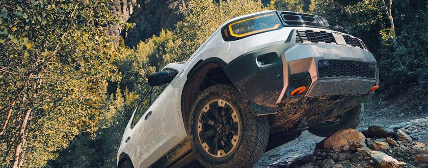 White 2026 Honda Passport driving up rocks.