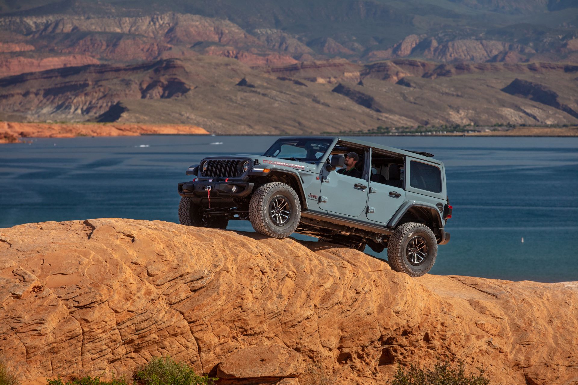 a blue jeep wrangler driving over rocky terrain