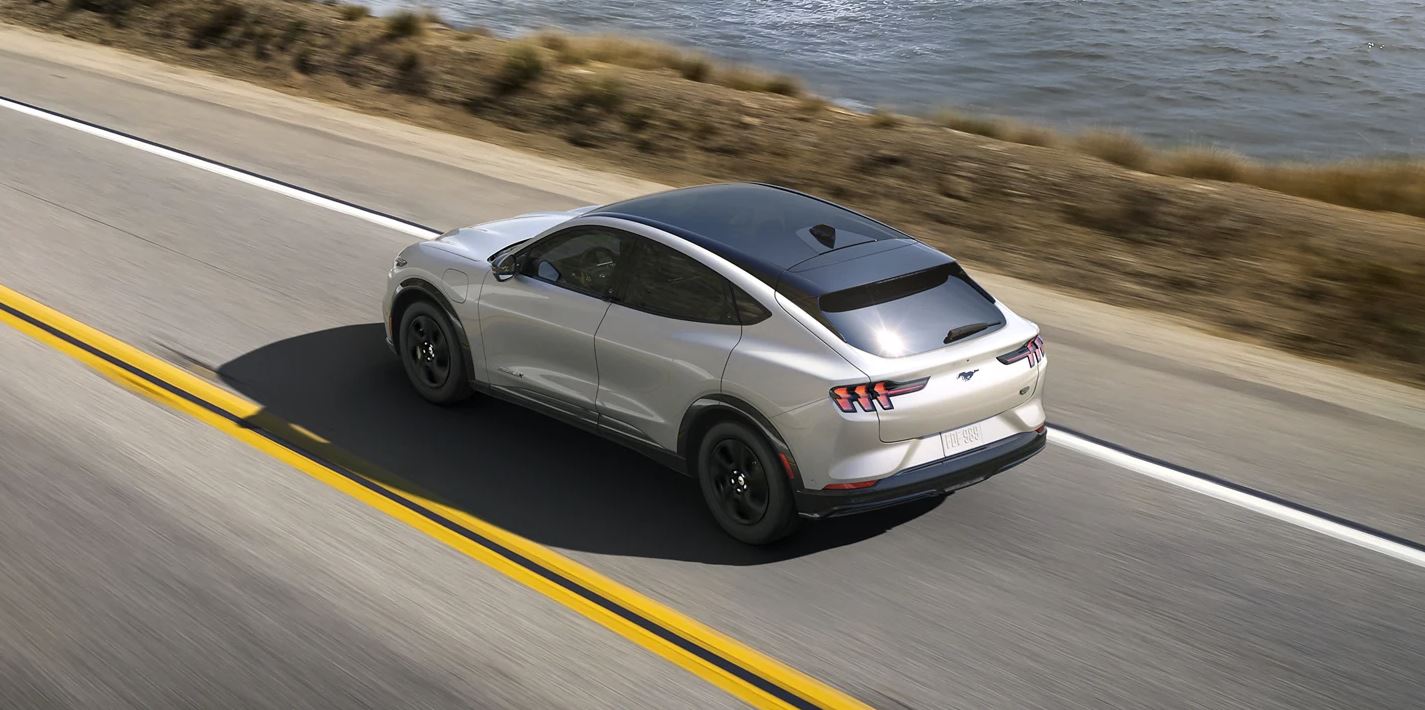 2023 Ford Mach-E driving down an oceanside highway