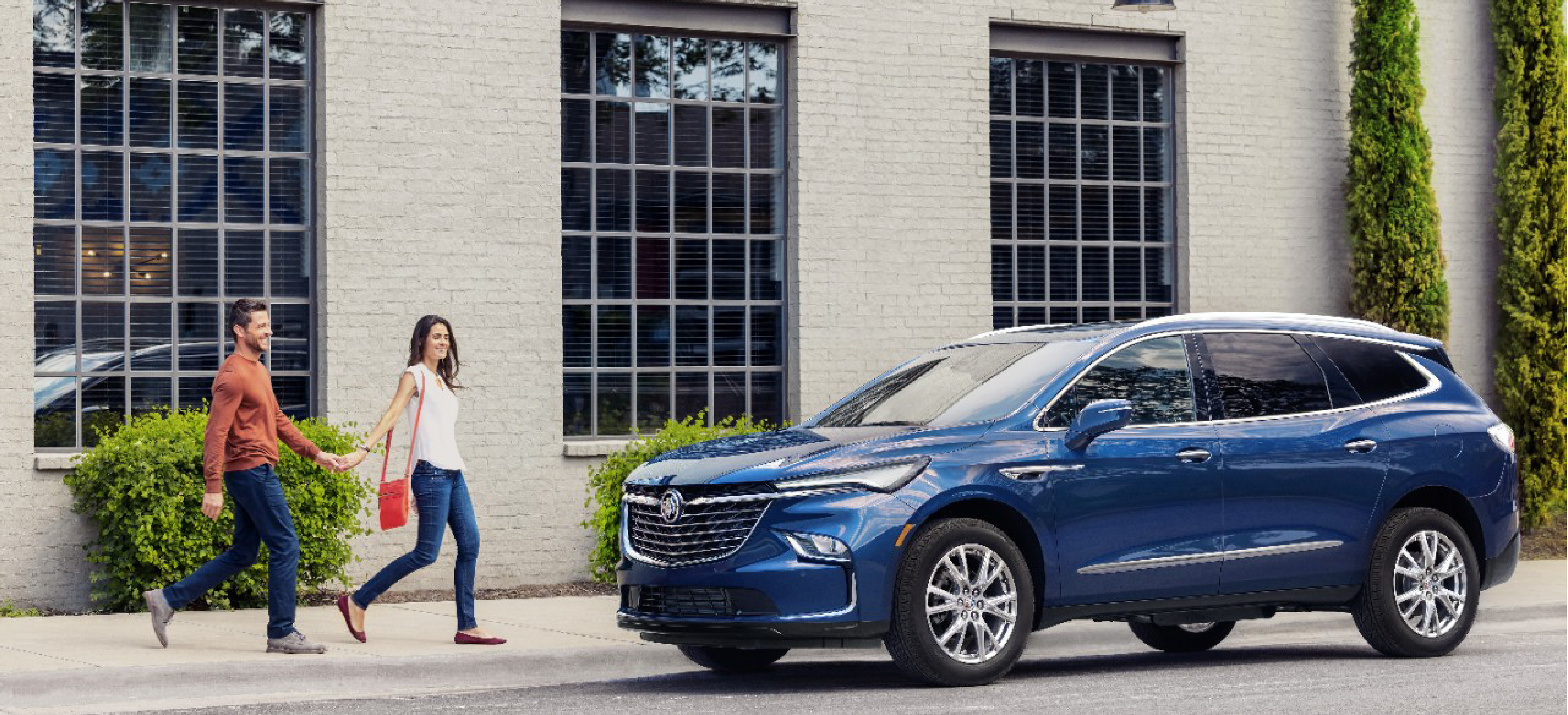 a couple is holding hands and walking towards a buick