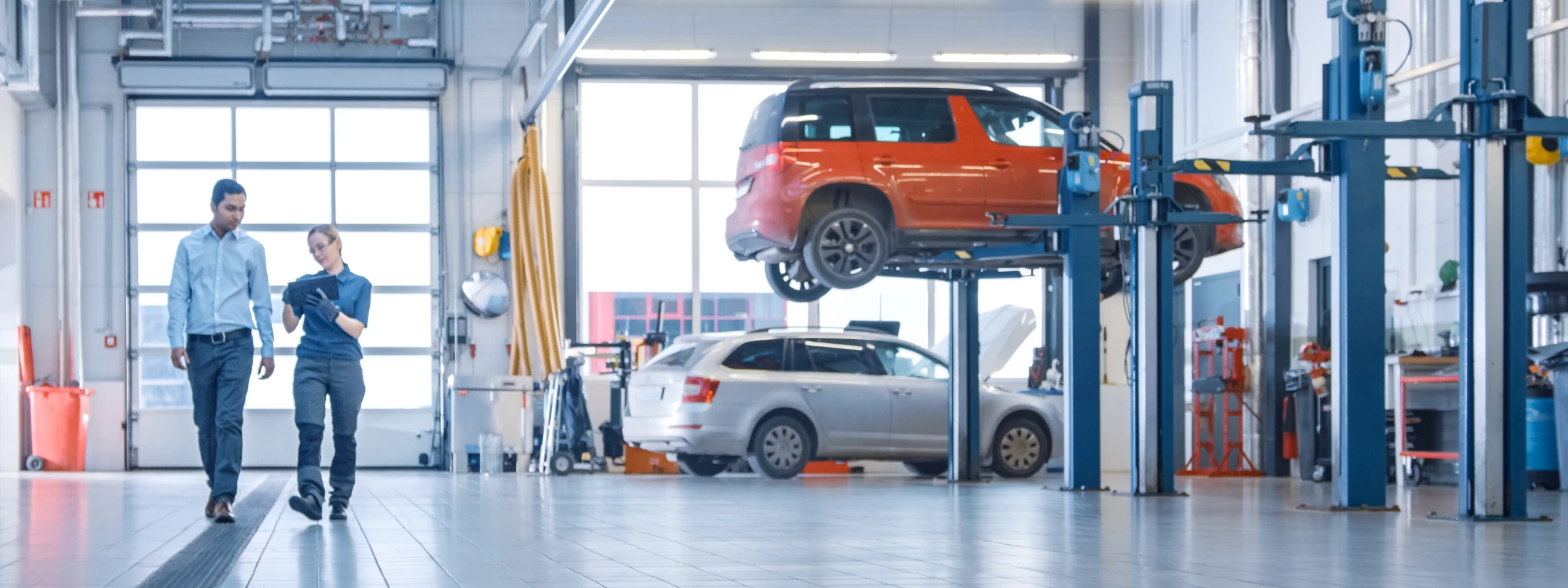 Two people walking through a car repair shop