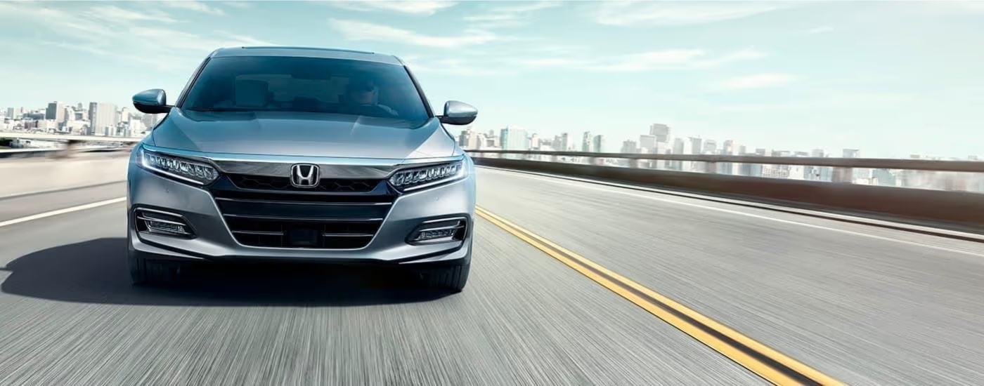 Silver 2020 Honda Accord driving away from a city
