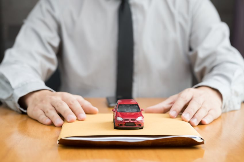 Man wearing a tie, with a manila envelope and red toy car