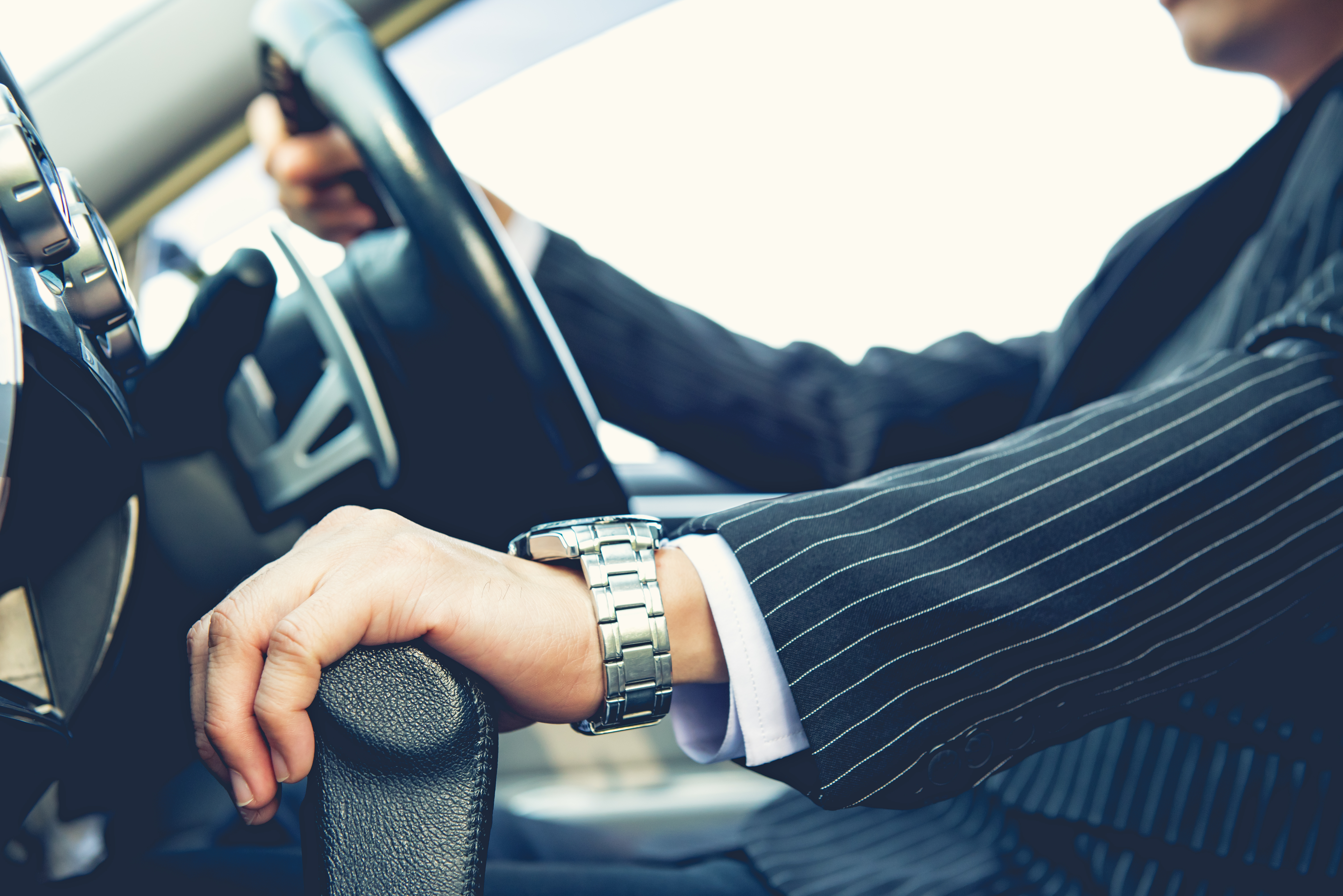 man with watch hand on steering wheel