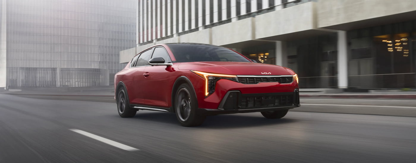 Red 2026 Kia K4 driving down a road.