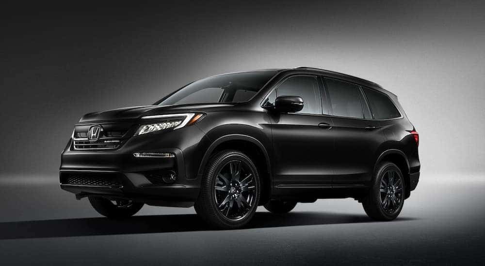 Black 2020 Honda Pilot Black Edition from the side with a gradient background.