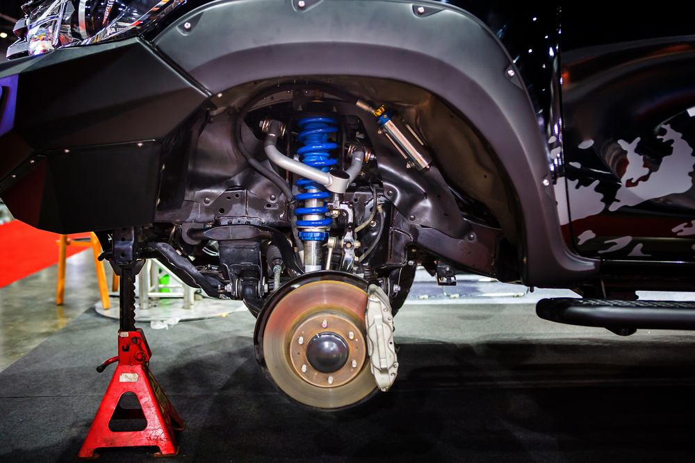 The Front left Wheelwell of a car is shows, the Tire has been taken off and we can see the inside of the car, including its blue shock absorbers