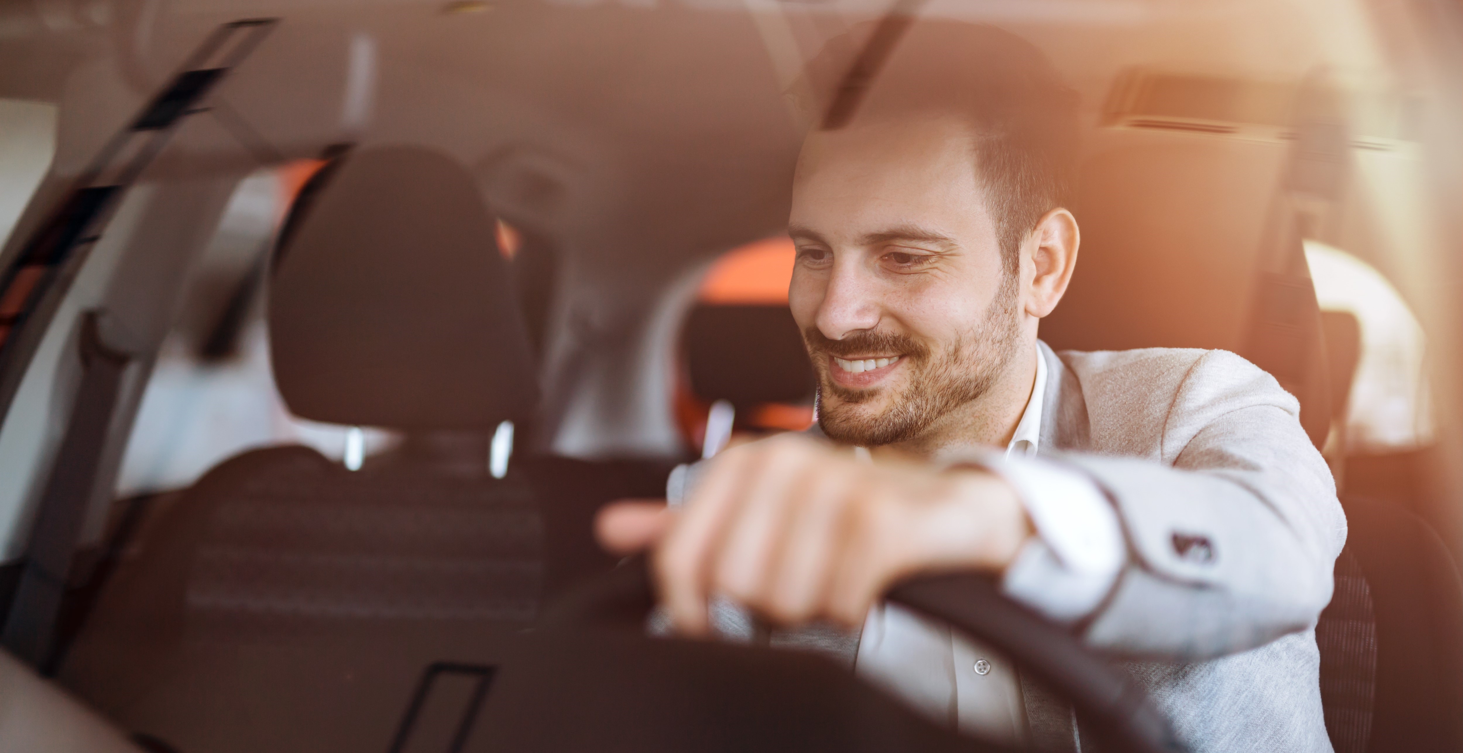 man smiling while changing the music playing in his car