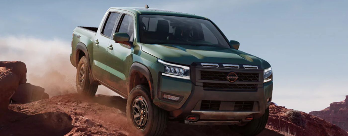Green 2026 Nissan Frontier PRO-4X driving off-road down a hill.