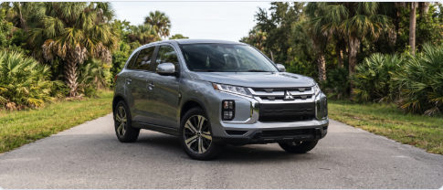 Silver Mitsubishi Outlander Sport SUV parked on a paved road surrounded by lush tropical palm trees.
