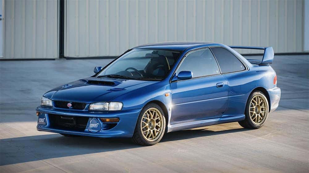 Blue 1998 Subaru Impreza 22B STi parked in front of a hangar