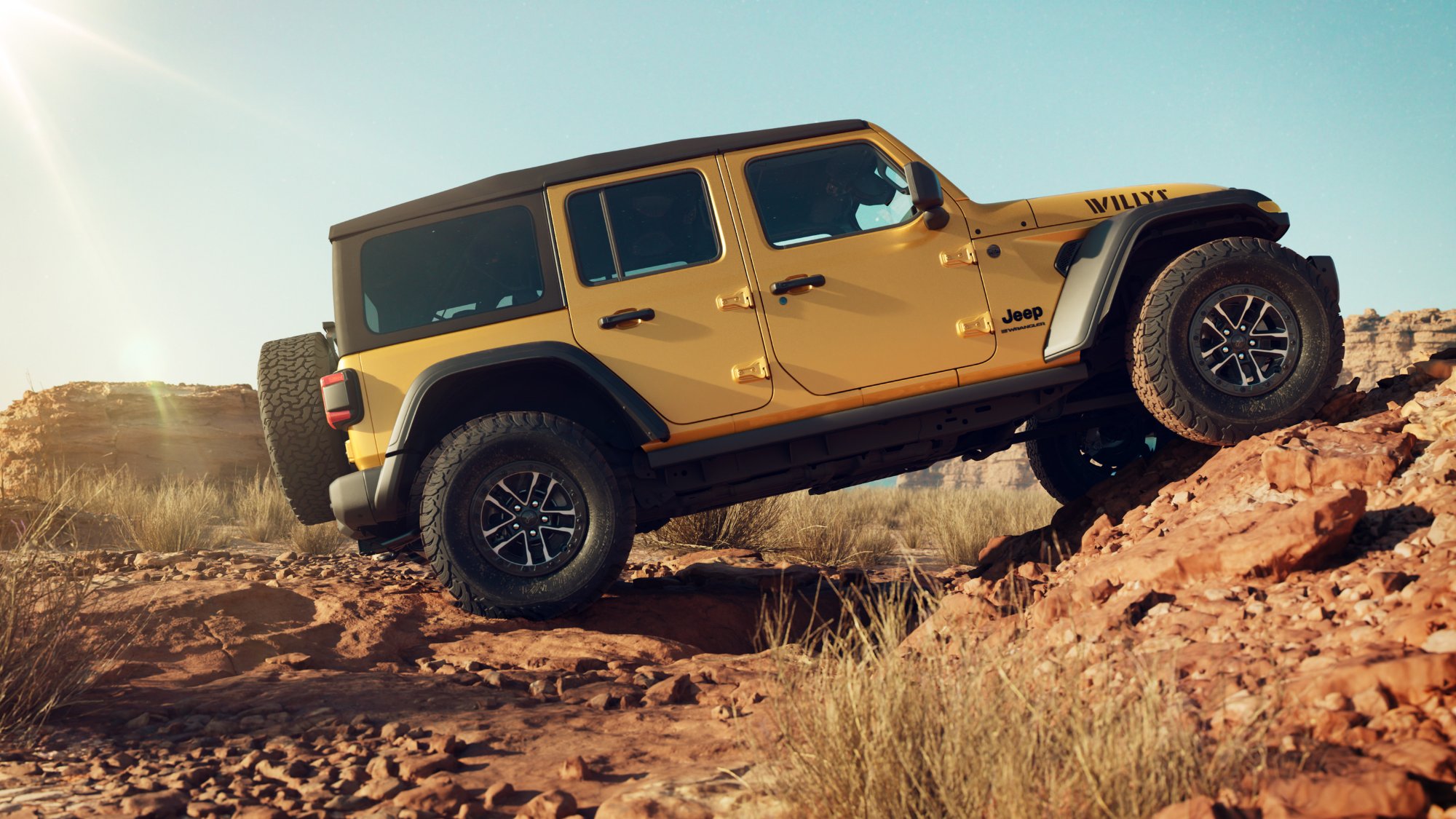 Yellow 2026 Jeep Wrangler with a hardtop climbing a dirt hill in the desert
