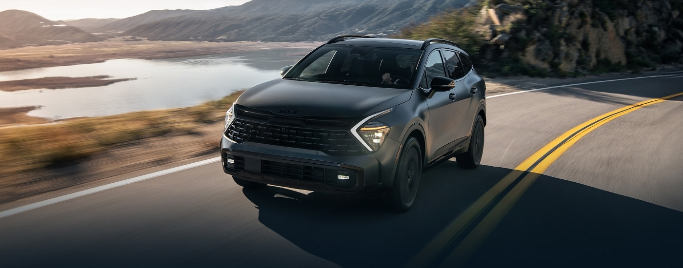 Grey 2025 Kia Sportage PHEV driving past a lake