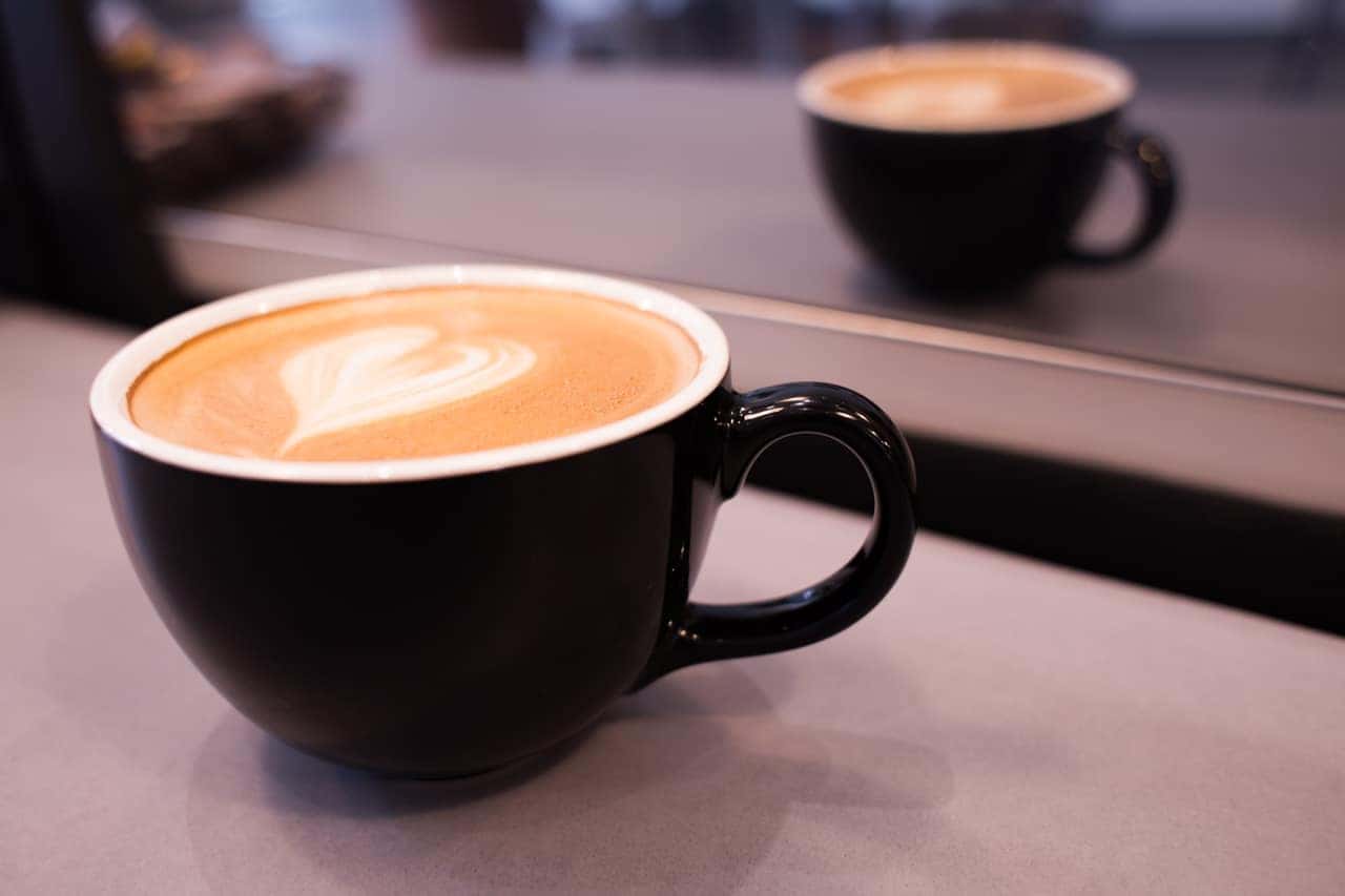 Latte with heart-shaped latte art in a black cup at the Outback Café