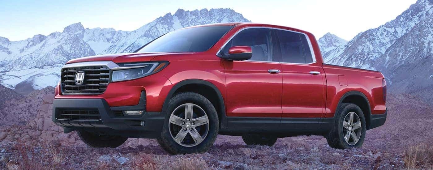 A red 2021 Honda Ridgeline RTL-E is shown from the side parked in the mountains.