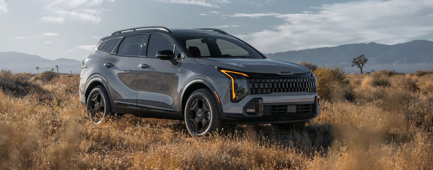 Grey Kia Sportage parked off-road in a desert field.