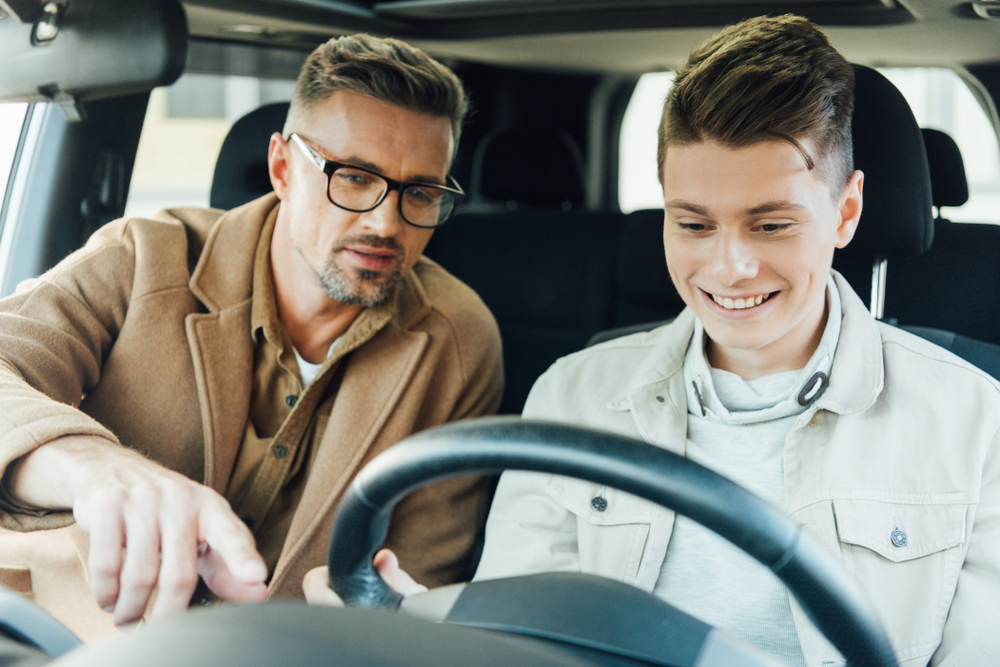 father teaching son how to drive a car